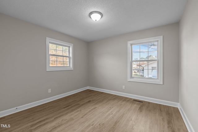 spare room with light wood-type flooring and a textured ceiling