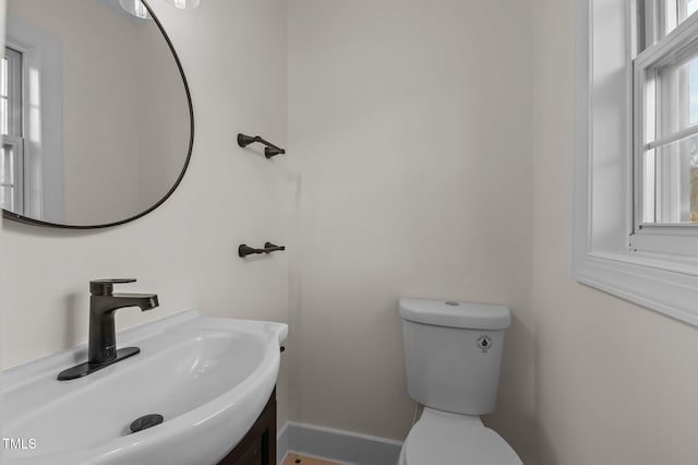 bathroom with toilet, sink, and a wealth of natural light