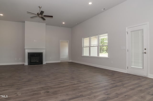 unfurnished living room with ceiling fan, dark hardwood / wood-style flooring, and a towering ceiling