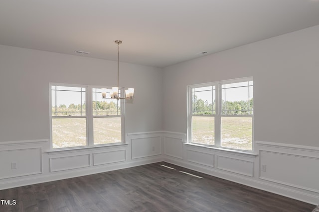 unfurnished dining area with dark wood-type flooring and an inviting chandelier