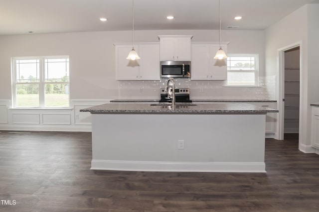 kitchen with white cabinetry, pendant lighting, stainless steel appliances, and an island with sink