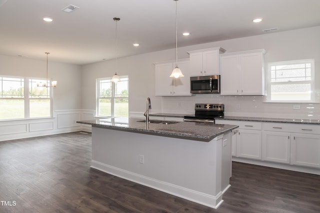 kitchen with decorative light fixtures, white cabinetry, stainless steel appliances, sink, and a center island with sink