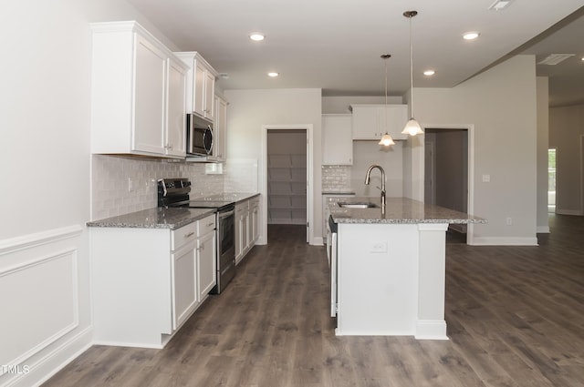 kitchen with an island with sink, appliances with stainless steel finishes, pendant lighting, white cabinets, and sink