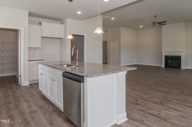 kitchen with stainless steel dishwasher, sink, white cabinetry, an island with sink, and light stone counters