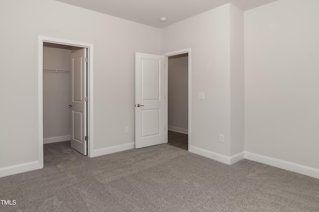 unfurnished bedroom featuring a spacious closet, a closet, and carpet