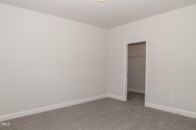 unfurnished bedroom featuring a closet, a spacious closet, and carpet flooring