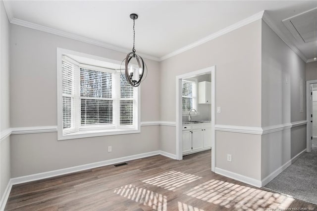 unfurnished dining area featuring a notable chandelier, hardwood / wood-style flooring, sink, and ornamental molding