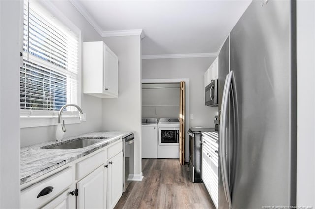 kitchen with stainless steel appliances, sink, light stone counters, white cabinets, and separate washer and dryer