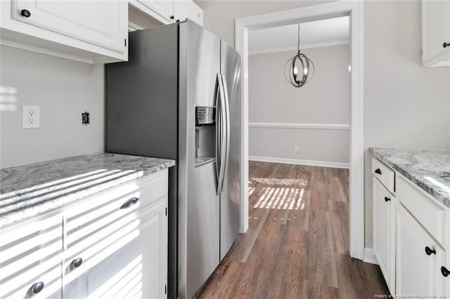 kitchen featuring decorative light fixtures, stainless steel fridge, ornamental molding, light stone counters, and white cabinets