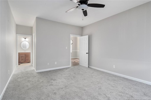 unfurnished bedroom featuring ceiling fan, ensuite bath, and light colored carpet