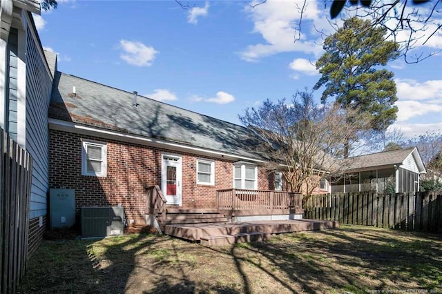 rear view of property featuring a deck, central AC unit, and a lawn