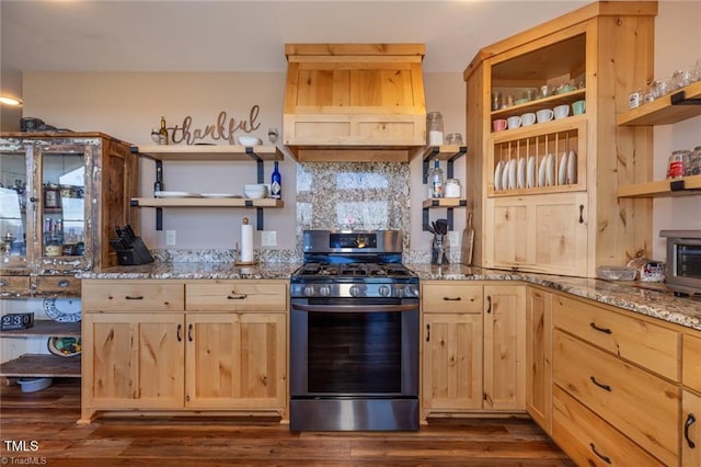 kitchen featuring light brown cabinetry, dark hardwood / wood-style flooring, premium range hood, dark stone counters, and stainless steel range with gas cooktop