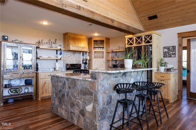 kitchen featuring light stone countertops, a breakfast bar, custom range hood, vaulted ceiling, and stainless steel gas stove