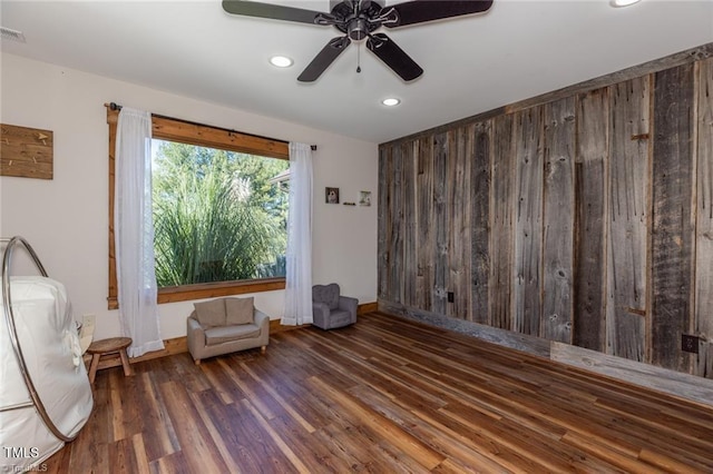 unfurnished room with ceiling fan, dark hardwood / wood-style floors, and wooden walls