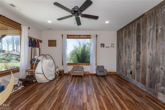 unfurnished room with ceiling fan, dark hardwood / wood-style flooring, and wood walls