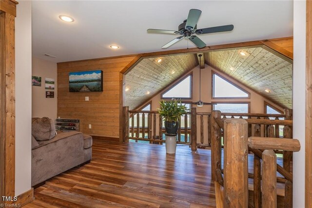 living room with vaulted ceiling with beams, ceiling fan, dark wood-type flooring, and wooden walls