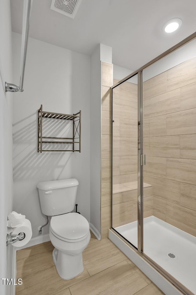 bathroom featuring a shower with shower door and toilet