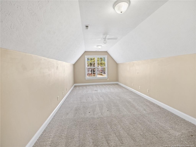 additional living space with carpet, ceiling fan, lofted ceiling, and a textured ceiling