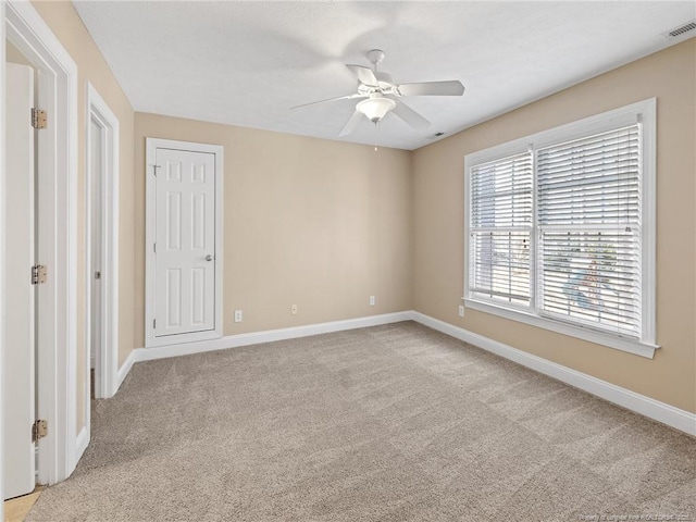 unfurnished room with light colored carpet and ceiling fan