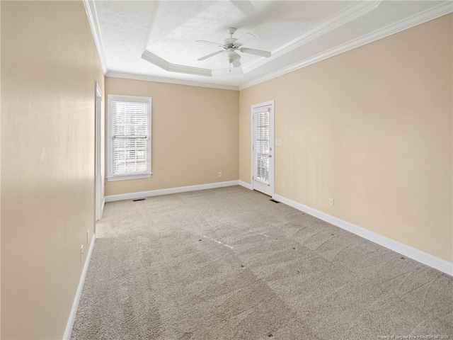 carpeted empty room with a raised ceiling, ceiling fan, and ornamental molding