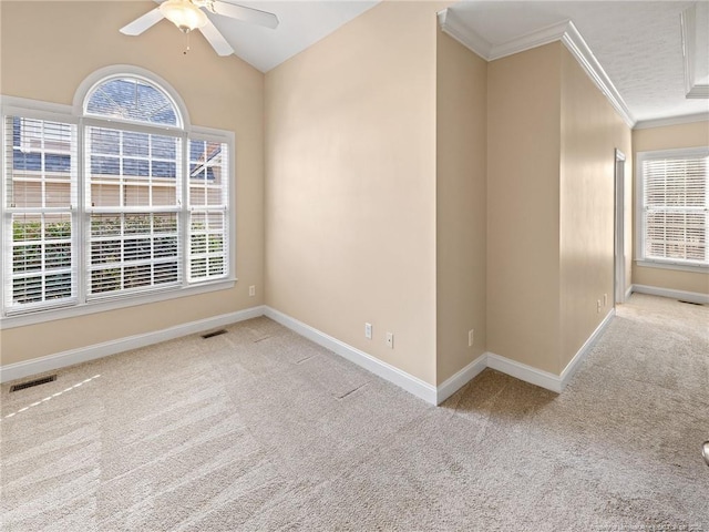 carpeted empty room with ceiling fan, plenty of natural light, crown molding, and vaulted ceiling