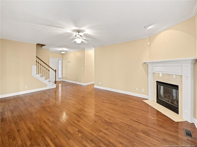 unfurnished living room featuring a high end fireplace, wood-type flooring, ceiling fan, and ornamental molding