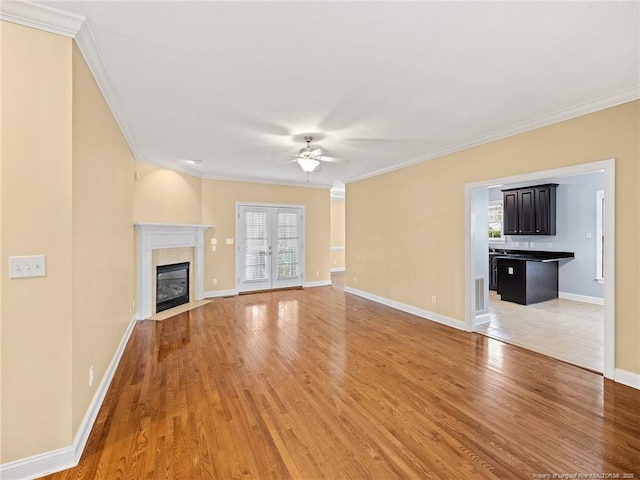 unfurnished living room with ceiling fan, ornamental molding, french doors, and light hardwood / wood-style flooring