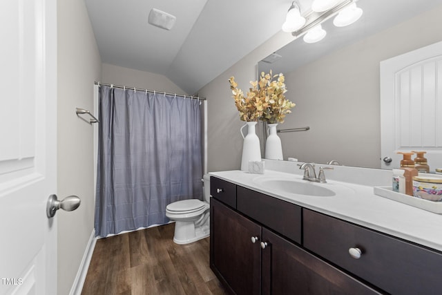 bathroom with hardwood / wood-style flooring, vanity, toilet, and lofted ceiling