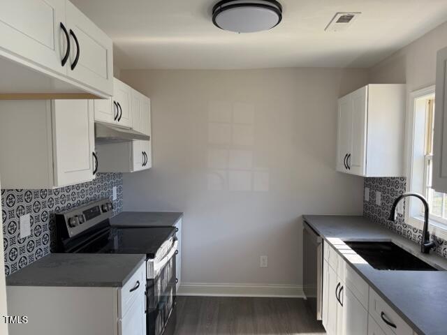 kitchen with white cabinets, sink, dark hardwood / wood-style floors, appliances with stainless steel finishes, and tasteful backsplash