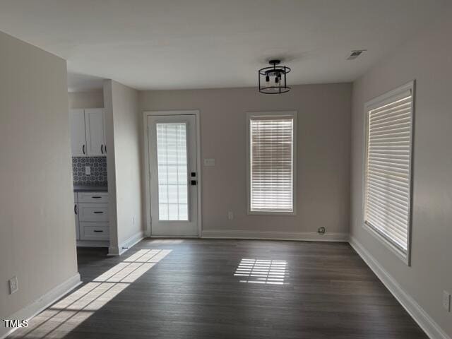 unfurnished dining area featuring dark wood-type flooring