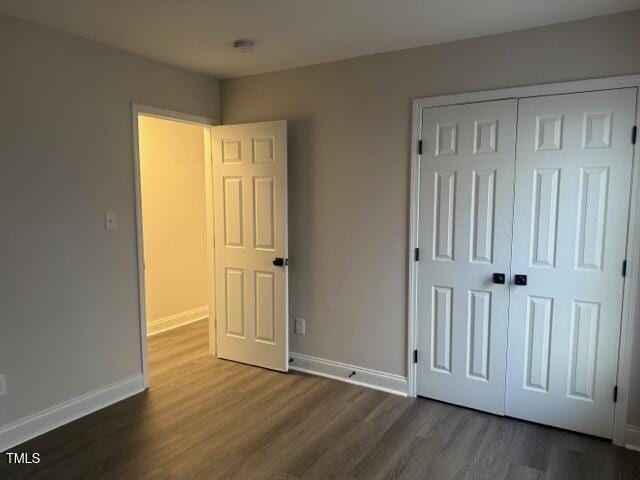 unfurnished bedroom featuring dark hardwood / wood-style flooring and a closet