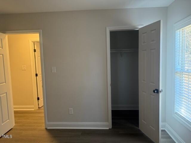 unfurnished bedroom featuring dark hardwood / wood-style flooring and a closet