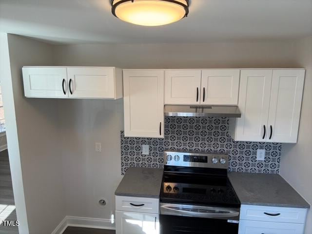 kitchen featuring white cabinets, tasteful backsplash, hardwood / wood-style flooring, and electric stove