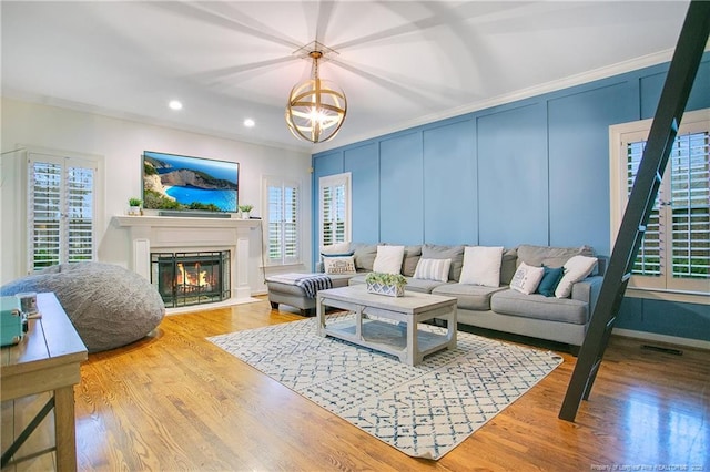 living room featuring wood-type flooring, an inviting chandelier, and crown molding