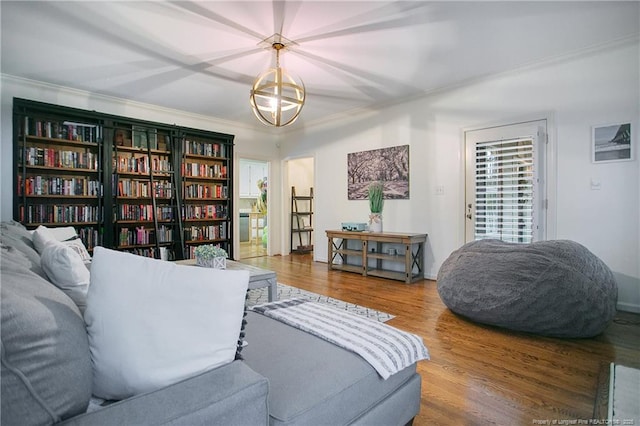 living area with hardwood / wood-style flooring, an inviting chandelier, and crown molding