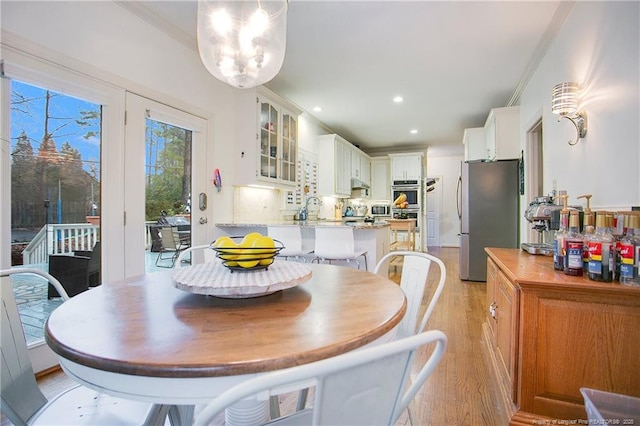 dining space with light hardwood / wood-style flooring, ornamental molding, and sink