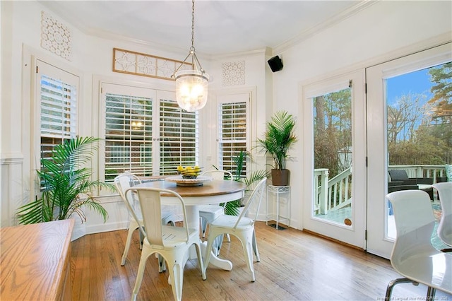 dining space with wood-type flooring, ornamental molding, and a chandelier