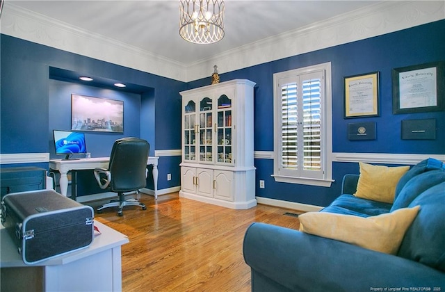 office with light hardwood / wood-style floors, ornamental molding, and a chandelier