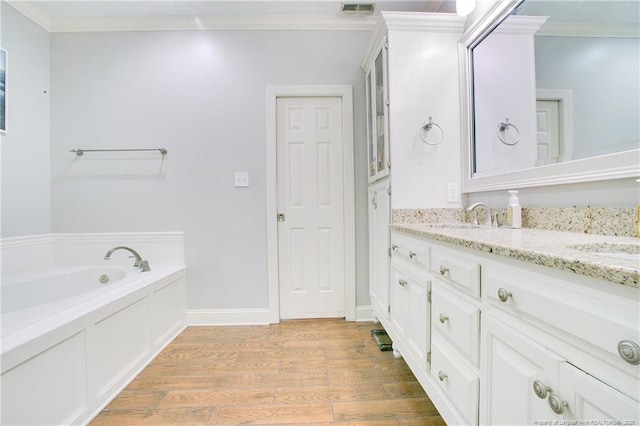 bathroom featuring vanity, hardwood / wood-style flooring, a bathtub, and crown molding