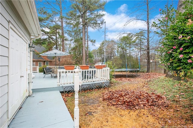 view of yard with a wooden deck and a trampoline