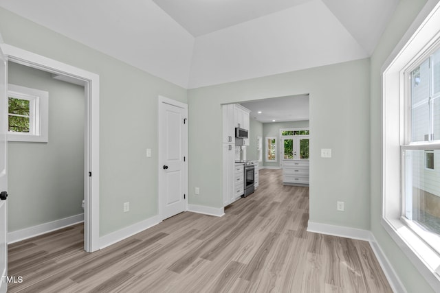 unfurnished room with vaulted ceiling and light wood-type flooring