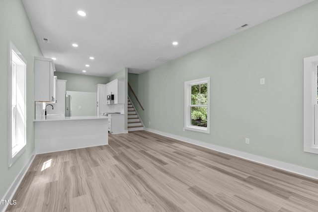 unfurnished living room with sink and light hardwood / wood-style flooring