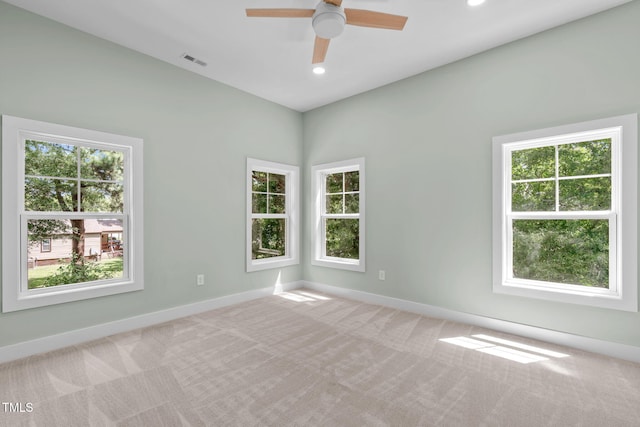 unfurnished room featuring a healthy amount of sunlight, light colored carpet, and ceiling fan