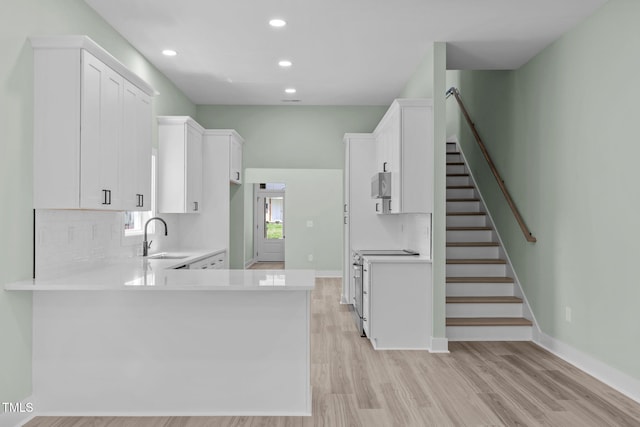 kitchen with sink, white cabinets, decorative backsplash, kitchen peninsula, and light wood-type flooring