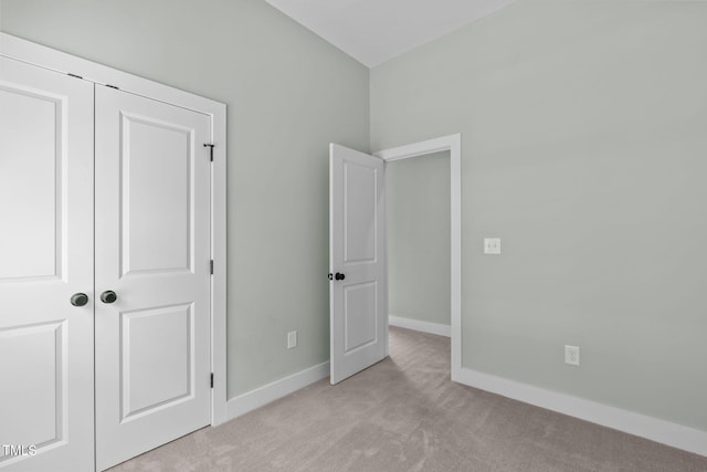 unfurnished bedroom with light carpet and a closet