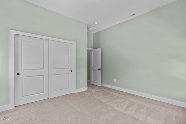 unfurnished bedroom featuring light colored carpet and a closet