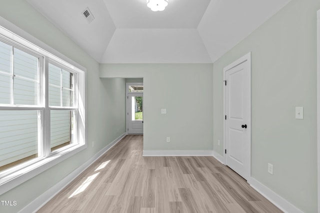 unfurnished room with vaulted ceiling and light wood-type flooring