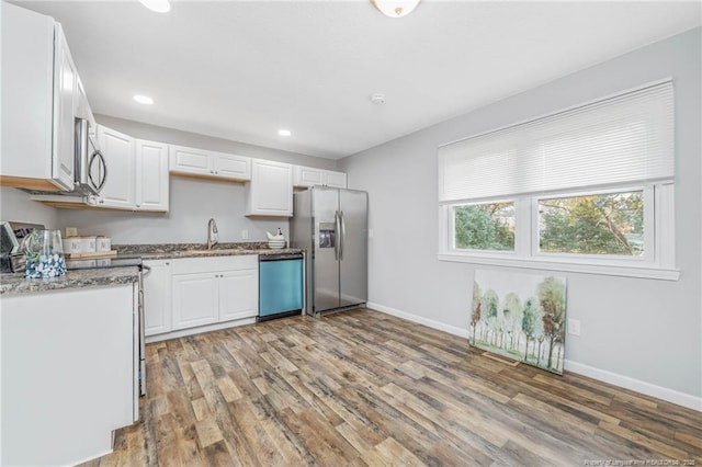 kitchen with stone counters, white cabinetry, sink, stainless steel appliances, and light wood-type flooring