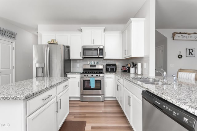 kitchen featuring sink, stainless steel appliances, light stone counters, decorative backsplash, and white cabinets