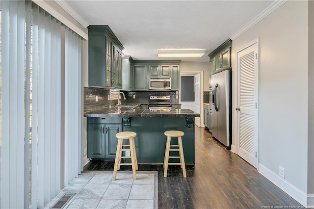 kitchen featuring ornamental molding, tasteful backsplash, a kitchen bar, kitchen peninsula, and stainless steel appliances